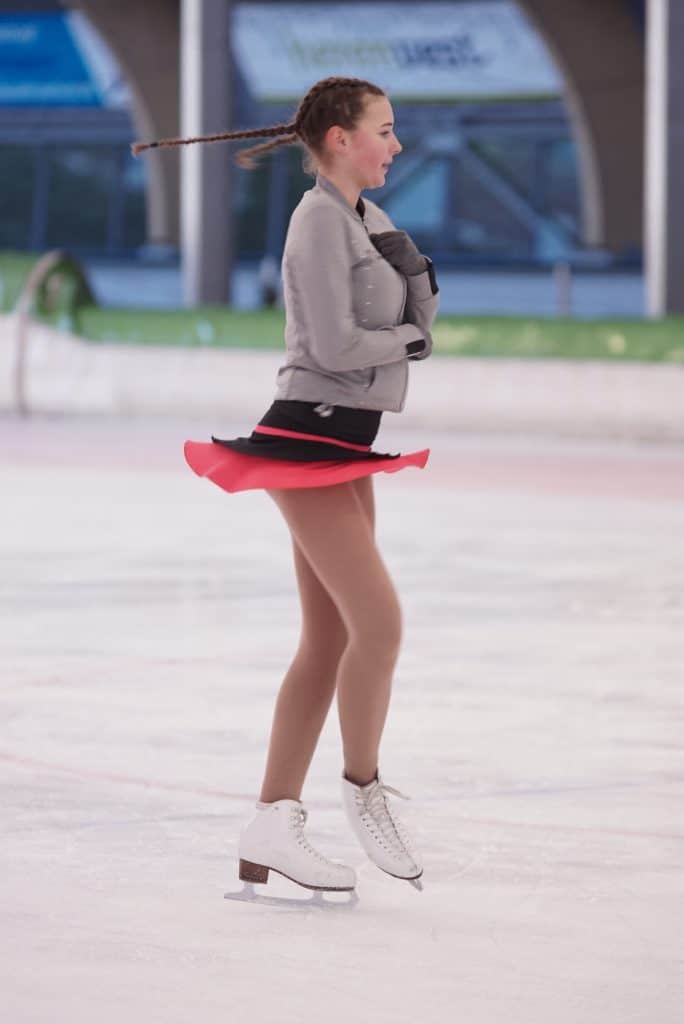 Een lid van de Kunstschaatsvereniging Haarlem draait bij het kunstschaatsen een pirouette.