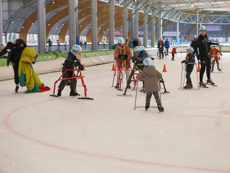 Foto van kinderen met een schaatsframe. Ook voor kinderen met een schaatsframe is er nu ijsplezier